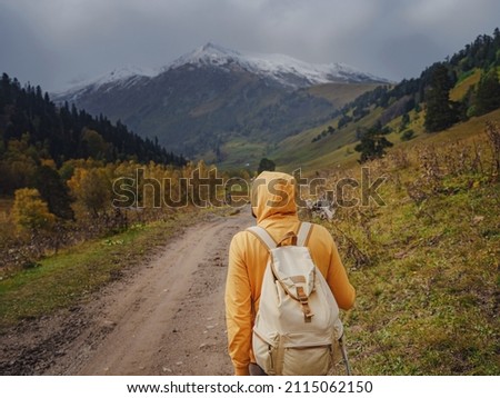 Man hikes mountains with travel backpack. Wandering lifestyle, adventure concept autumn vacation outdoors, alone in wild. Travel to North Caucasus, Arkhyz, Russia. road to Dukkinsky lakes Royalty-Free Stock Photo #2115062150