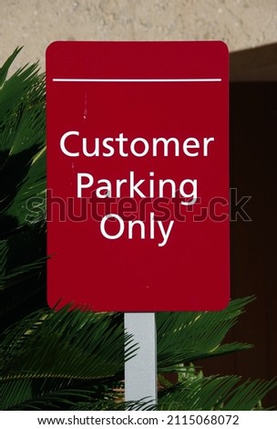 Red sign CUSTOMER PARKING ONLY posted at a business parking lot