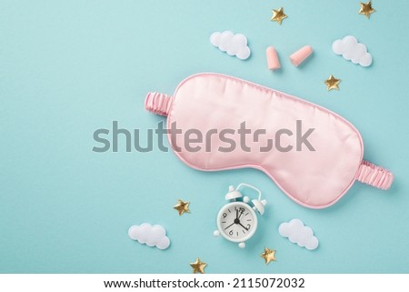 Top view photo of pink satin sleeping mask alarm clock earplugs clouds and golden stars on isolated pastel blue background with copyspace Royalty-Free Stock Photo #2115072032
