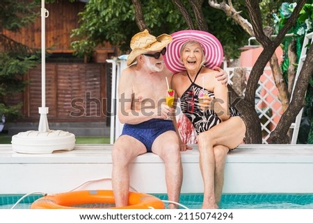 Happy senior couple having party in the swimming pool - Elderly friends releaxing at a pool party during summer vacation Royalty-Free Stock Photo #2115074294