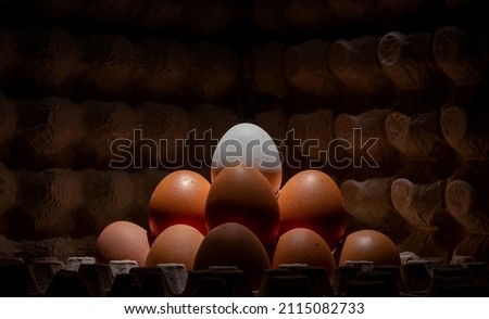 A red white chicken egg in a cardboard textured paper package laid out in a heap on the market for sale. The image is a contrasting close-up.