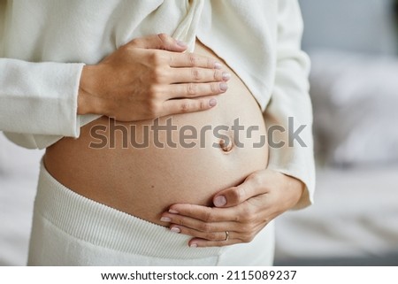 Close-up of young pregnant woman touching her belly and caring about her health Royalty-Free Stock Photo #2115089237
