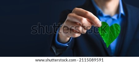 Businessman holding a green heart leaf  Business with corporate social responsibility and environmental concern. Environmental and Ecology Care Concept.. ESG Concept. Nature 