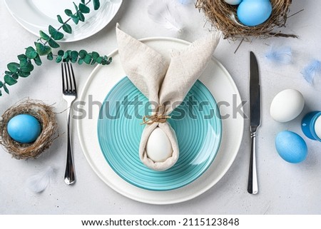Festive Easter table setting with Easter bunny made of linen napkin and egg. Top view. Royalty-Free Stock Photo #2115123848