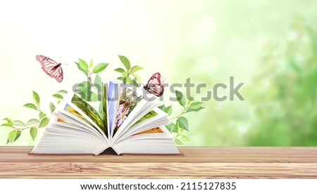 Book of nature. Horizontal banner with book open and two Monarch butterflies on wood table. Knowledge, education, ecology and environment concept. Copy space for text