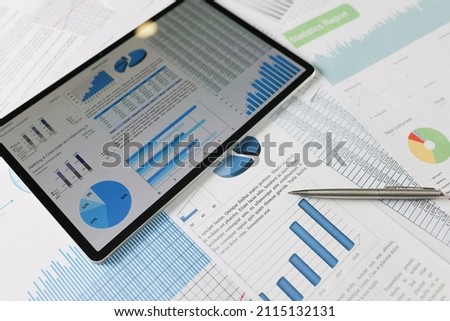 On statistical reports lies a tablet with charts on the screen Royalty-Free Stock Photo #2115132131