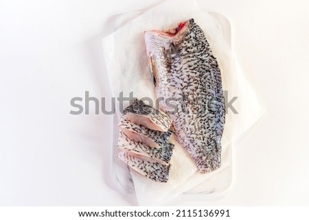 Fresh sea bass fish fillets on marble cutting board; selective focus and copy space. Royalty-Free Stock Photo #2115136991