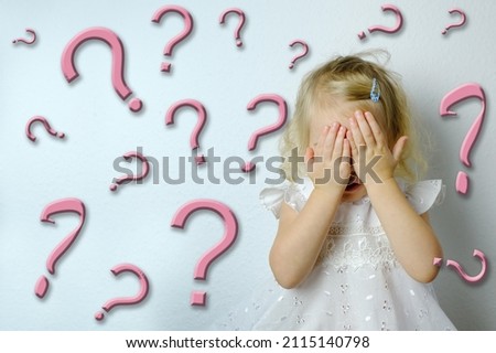 small child, blonde girl 2 years old in white dress covered her eyes with her hands, many question marks, concept of children's whims, parental abuse, psychological violence, difficult childhood Royalty-Free Stock Photo #2115140798
