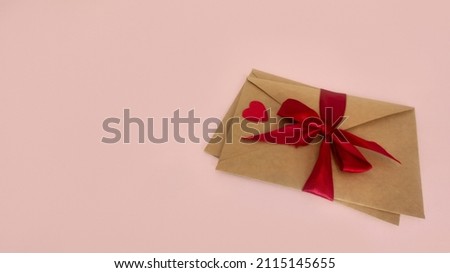 Several craft envelopes tied with a red ribbon red paper heart postcard for valentine's day on a pink background isolate. Concept: design valentine's day postcard mocap copy space for designer 