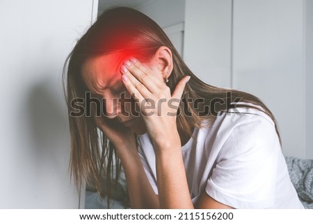 Young woman touching her temples and suffering from head pain, headache or migraine Royalty-Free Stock Photo #2115156200