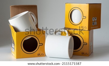 Mug cup and its storage container. One is inside, one is outside, and the other is on the box. Ready to ship mug and shipping box. It is suitable for the use of mug printing and mug sales companies. Royalty-Free Stock Photo #2115171587
