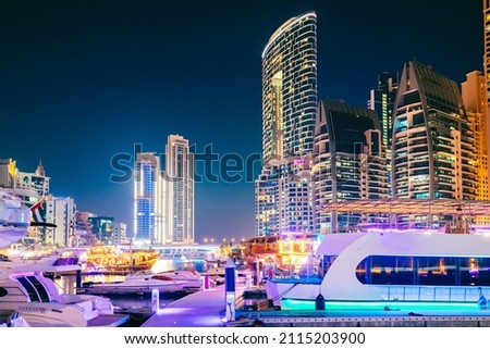 Night view of skyscraper in Dubai Marina And Boats, Yachts Moored Near Pier In Evening Night Illuminations. Royalty-Free Stock Photo #2115203900