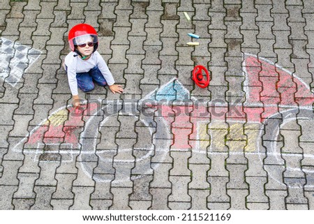 Creative leisure for children: Funny little child of four years having fun with race care picture drawing with chalk.