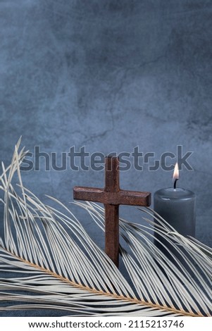 Catholic Cross with palm leaf and burning candle. Ash Wednesday, Lent season, Holy Week, Good Friday and Palm Sunday concept. Copy space. Royalty-Free Stock Photo #2115213746
