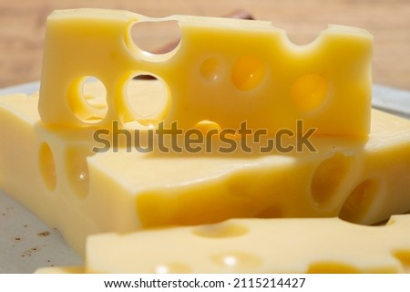Cheese collection, blocks of French emmentaler cheese with many round holes made from cow milk close up Royalty-Free Stock Photo #2115214427