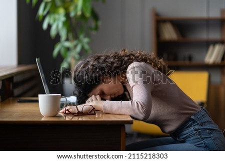 Overworked tired female student, freelancer or remote worker sleep lying on desk suffer from fatigue, computer work. Businesswoman feel exhausted from laptop, overwork and deadline. Selective focus Royalty-Free Stock Photo #2115218303