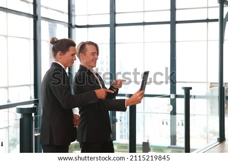 two young business people working and communicating while standing at the office with city building background.
