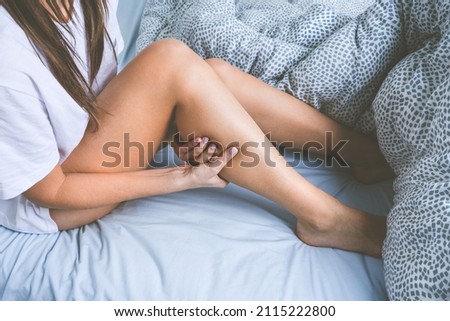 Woman lying in the bed and suffering from leg muscle cramps. Muscle pain or leg pain while sleeping Royalty-Free Stock Photo #2115222800