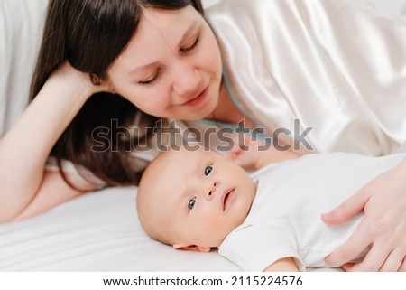 mom lies with the baby in bed. the happiness of motherhood. the benefits and harms of co-sleeping parents with newborns.