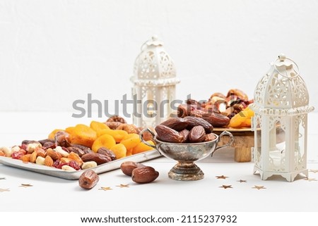 Ramadan Kareem and iftar muslim food, holiday concept. Trays with nuts and dried fruits and latterns with candles. Celebration idea Royalty-Free Stock Photo #2115237932
