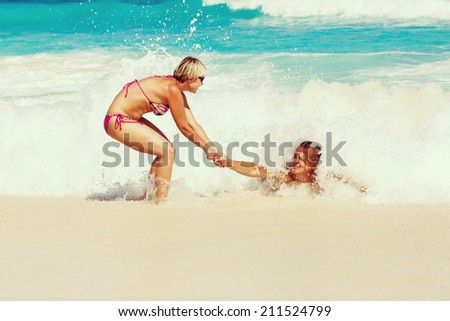 Young romantic couple, white young man and a young blonde girl with short hair with wearing glasses, have fun on sandy beautiful tropical beach Seychelles La Digue