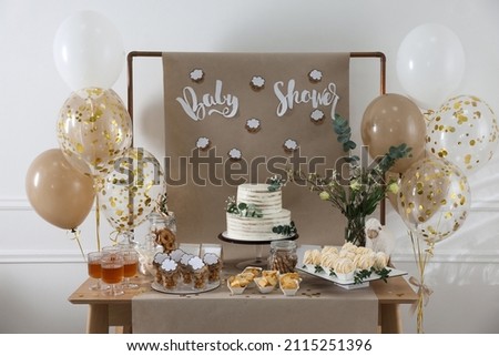 Beautiful cake and other treats on table in room. Baby shower party Royalty-Free Stock Photo #2115251396