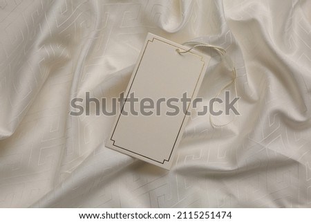 Blank tag on beige fabric, top view. Space for text