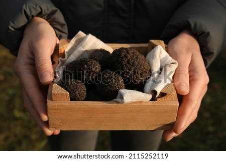 Woman holding wooden crate with truffles outdoors, closeup