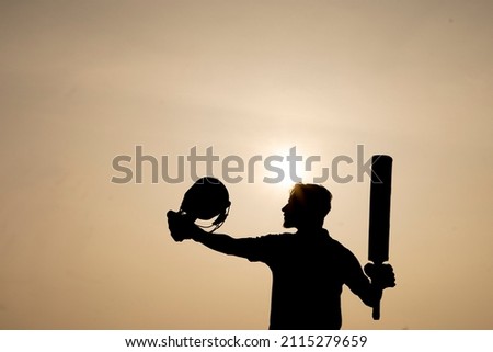 Silhouette of a cricketer celebrating after getting a century in the cricket match. Indian cricket players and sports concept.