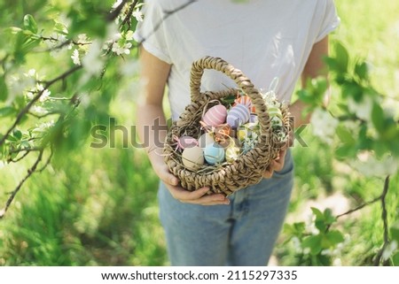 Easter egg hunt in spring garden. Funny teen girl with eggs basket and bunny ears on Easter egg hunt in sunny spring garden. Celebrating Easter. Happy easter card