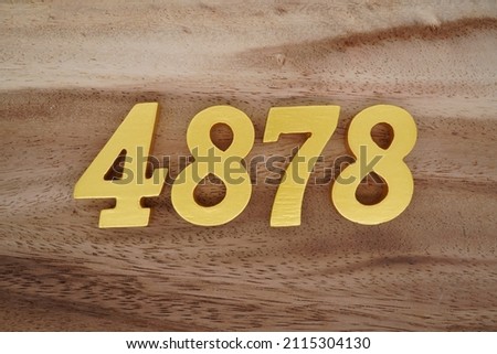 Wooden Arabic numerals 4878 painted in gold on a dark brown and white patterned plank background.