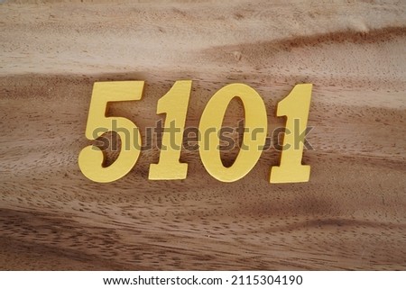 Wooden Arabic numerals 5101 painted in gold on a dark brown and white patterned plank background.