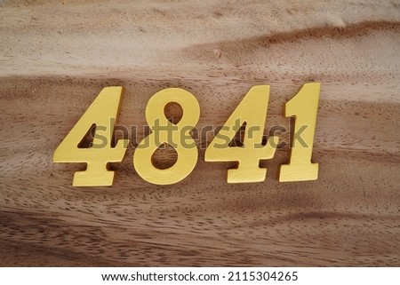 Wooden Arabic numerals 4841 painted in gold on a dark brown and white patterned plank background.