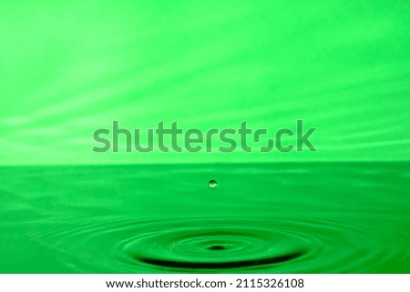 Splash water after drop falls.Green abstract background with drop in water