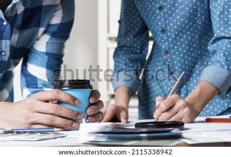 Woman writing with pen on technical drawing. Creative team of designers together working with construction blueprint. Thorough study and approval of design project. Architecture studio concept.