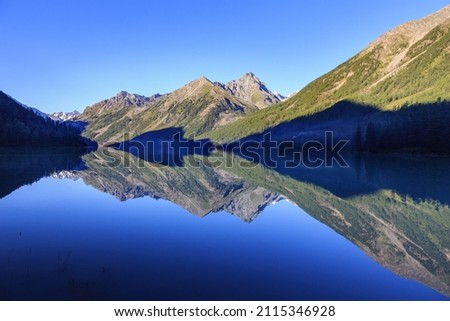 landscape with a flying arrow on the edge of Lake Kucherlinsky, formed by the shadow of mountains and reflection in the water in sunny weather in summer