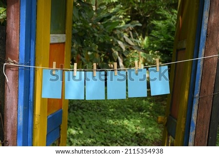 Blue cardboard paper hanging on a rope with wooden clips on a door outdoors