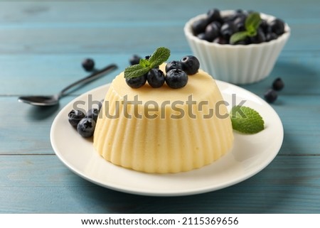 Delicious semolina pudding with blueberries on light blue wooden table Royalty-Free Stock Photo #2115369656