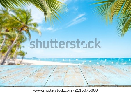 Top of wood table with seascape and palm tree, blur bokeh light of calm sea and sky at tropical beach background. Empty ready for your product display montage. summer vacation background concept. Royalty-Free Stock Photo #2115375800