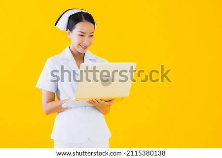 Portrait beautiful young asian woman thai nurse with laptop on yellow isolated background