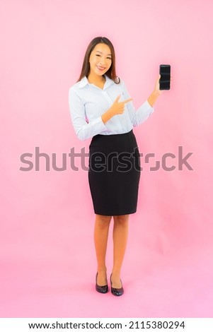 Portrait beautiful young asian woman use smart mobile phone on pink isolated background