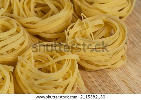Italian uncooked tagliatelle pasta on wooden table