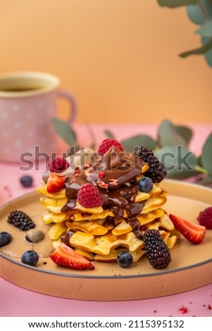 Waffle with with banana ice cream and chocolate. Delicious belgian waffles with berries on pink background. Coffee and dessert. Sweet food.
