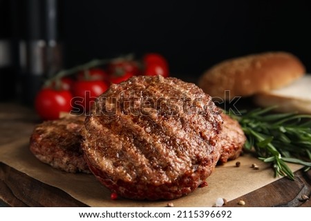 Tasty grilled hamburger patties with seasonings on wooden table, closeup