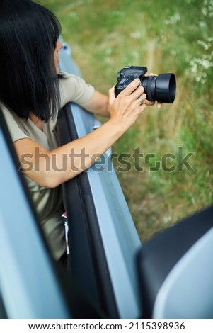 Woman photographer sitting in the car and photographing a flower field landscape, travel female take photo, space for text.