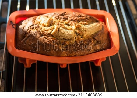 Homemade banana bread in red silicon baking pan on rack. Top view