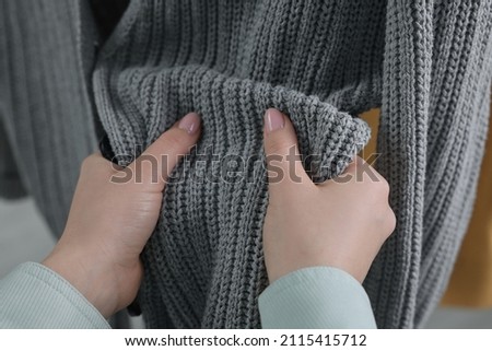 Woman touching clothes made of soft knitted fabric, closeup