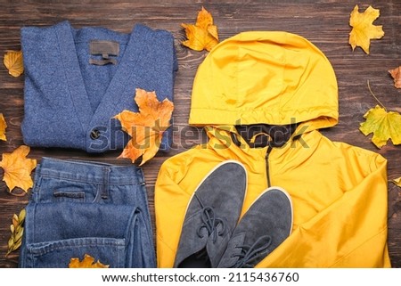 Stylish jacket, sweater, jeans, shoes and autumn leaves on wooden background Royalty-Free Stock Photo #2115436760