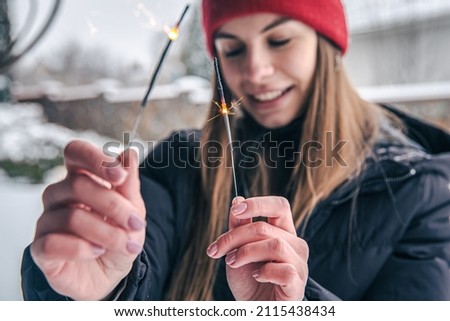 Close-up young woman holding sparklers in her hands.
