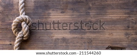 wooden board with a rough texture and a rope with a knot. Blank space for text